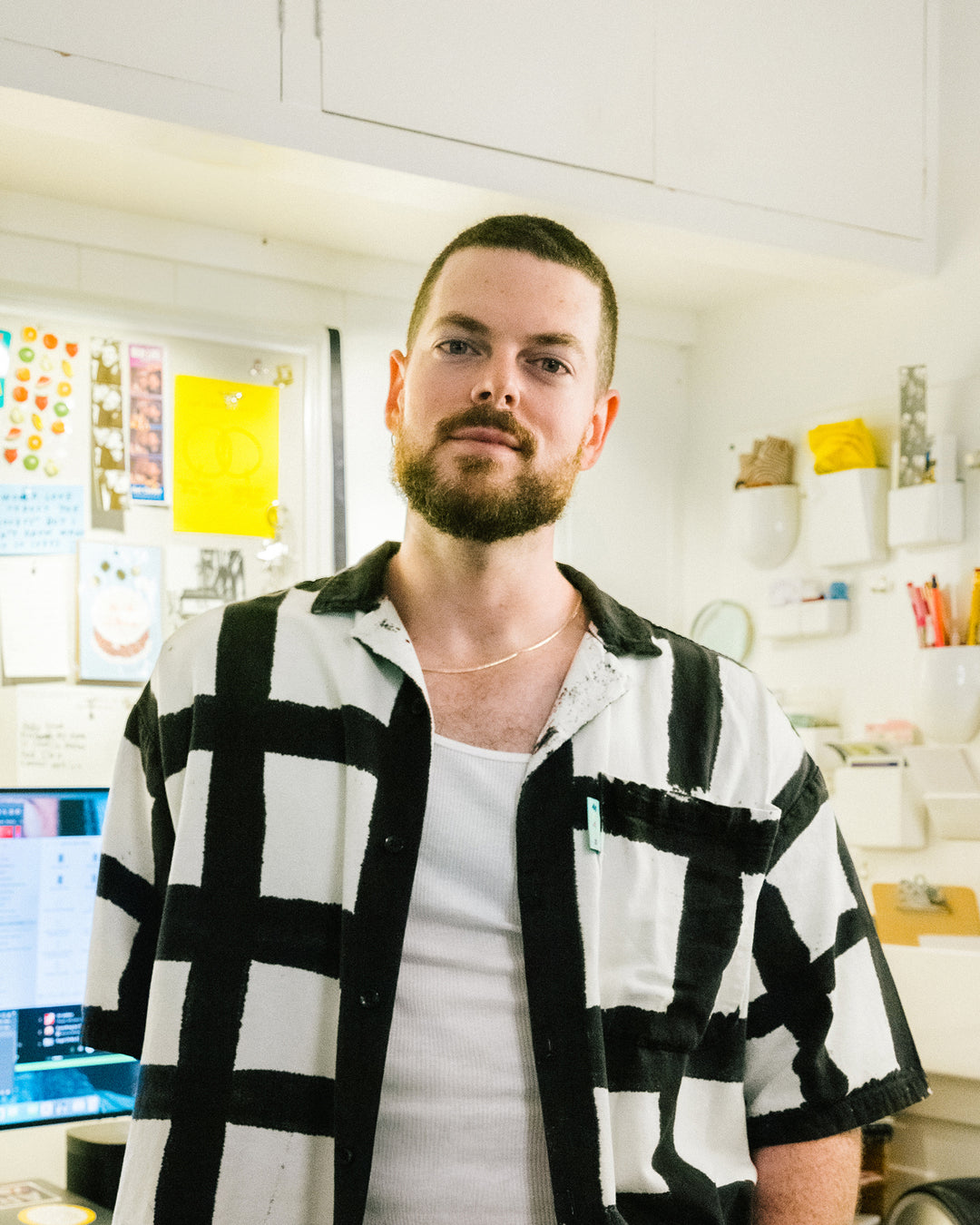 Portrait of Adam in black and white checkered shirt standing in creative office environment