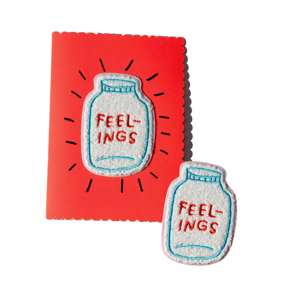 Red greeting card with removable chenille patch. Patch is shaped like a jar and says FEELINGS in red handwritten text. By Adam JK.