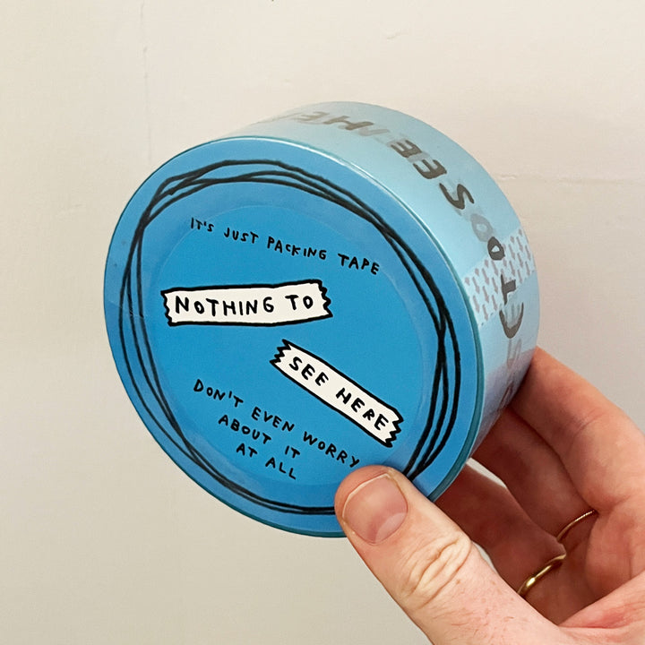 Blue packing tape reads "NOTHING TO SEE HERE" in Adam JK's signature handwriting