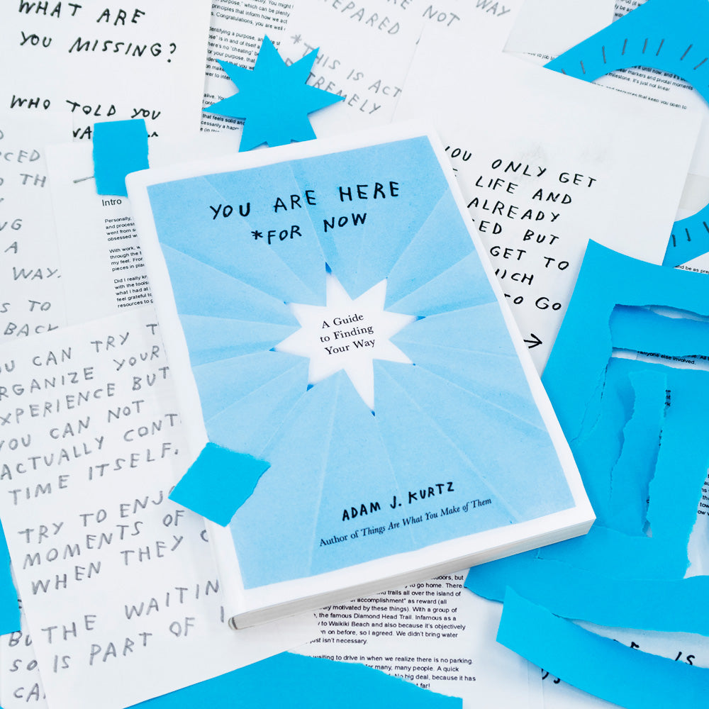 Photo of the book You Are Here (For Now) by Adam J. Kurtz shown in pile of art and paper from the creative process